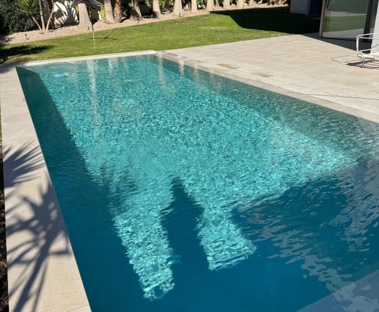 Pool Blauer Pool mit künstlerischem Mosaikdesign und Aussicht auf umgebende Bäume.